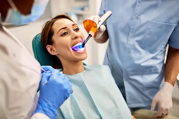 Dentist and assistant performing a dental bonding procedure on a female patient at D.A. Dental in Auburn, MA