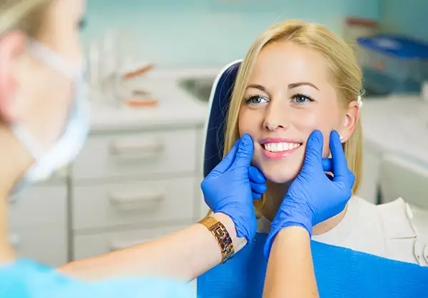 A dentist  checking a female patient's smile in a dental clinic at D.A. Dental in Auburn, MA
