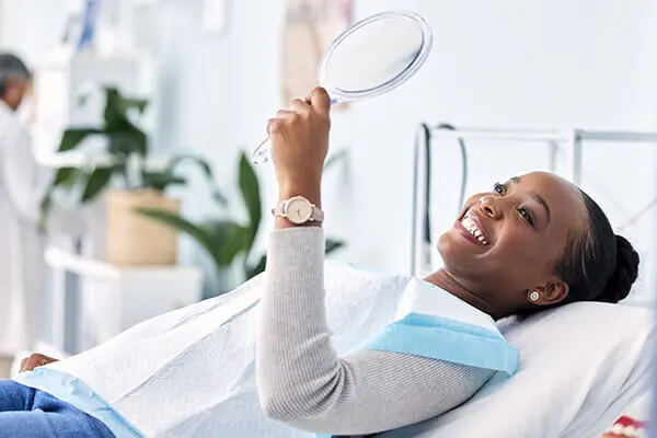 Smile, mirror and black woman at dentist on chair in clinic, tooth treatment and cleaning at D.A. Dental In Auburn, MA